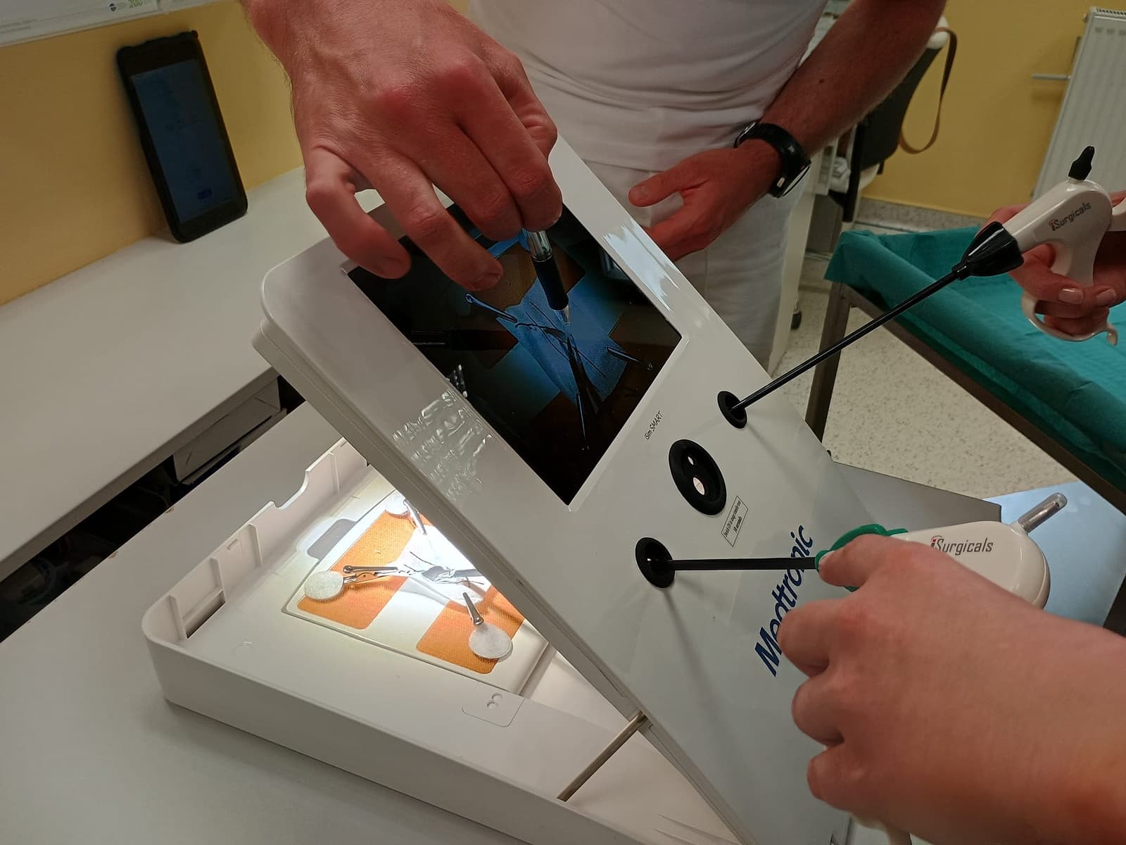 Hands using a laparoscopic medical training device
